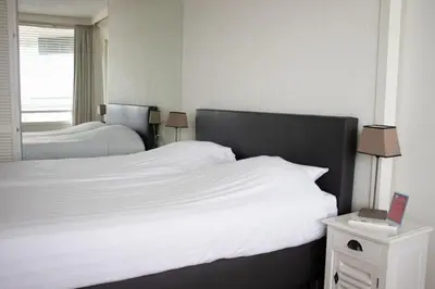 a bedroom with two beds with white sheets and a window at Sterflat 179 in Egmond aan Zee