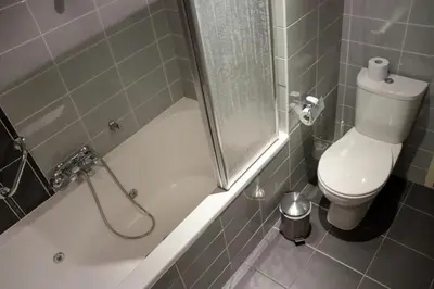 a bathroom with a toilet and a tub with a shower at Sterflat 179 in Egmond aan Zee