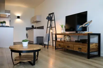 a living room with a flat screen tv on a wooden table at Sterflat 179 in Egmond aan Zee