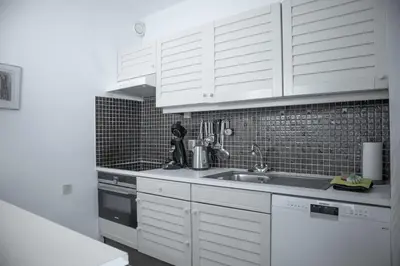a kitchen with white cabinets and a sink at Sterflat 185 in Egmond aan Zee