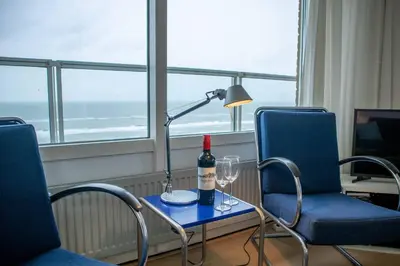 a table with a bottle of wine and two chairs at Sterflat 185 in Egmond aan Zee