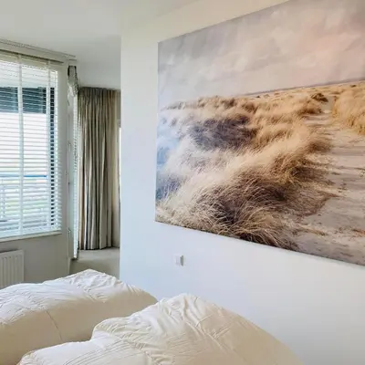 a bedroom with a painting hanging on the wall at Sterflat 189 in Egmond aan Zee