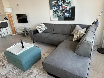 a living room with a gray couch and a blue ottoman at Sterflat 199 in Egmond aan Zee