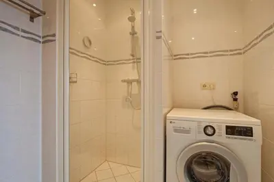 a washing machine in a bathroom with a shower at Sterflat 199 in Egmond aan Zee