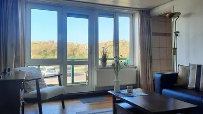 a living room with a large window and a table at Torenlicht in Egmond aan Zee