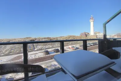 a table and chairs on a balcony with a lighthouse at Torenlicht in Egmond aan Zee