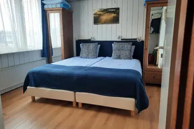 a bedroom with a large bed with a blue blanket at Torenlicht in Egmond aan Zee