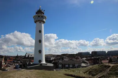 a lighthouse on a hill with a city in the background at Torenlicht in Egmond aan Zee