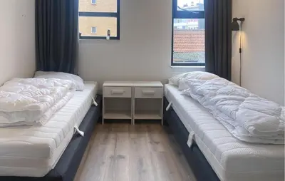 two beds in a room with a table and windows at Gorgeous Apartment In Bergen Aan Zee in Bergen aan Zee