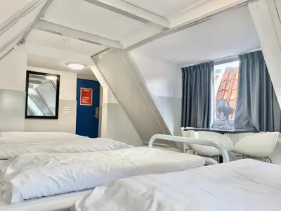 a room with two beds and a table and chairs at The White Tulip Hostel in Amsterdam