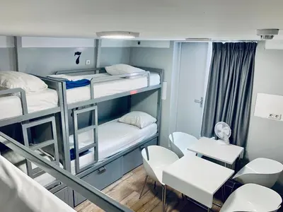 a room with bunk beds and a table and chairs at The White Tulip Hostel in Amsterdam