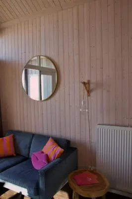 a living room with a blue couch and a mirror at Sisters Beachbungalows in Katwijk aan Zee