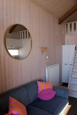 a living room with a blue couch and a mirror at Sisters Beachbungalows in Katwijk aan Zee