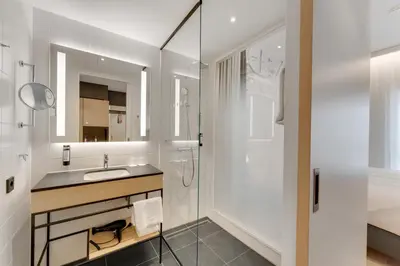 a white bathroom with a sink and a shower at IntercityHotel Leiden in Leiden