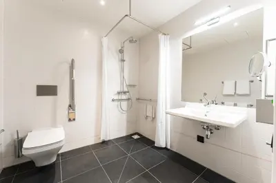 a white bathroom with a toilet and a sink at IntercityHotel Leiden in Leiden