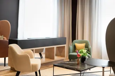 a living room with a piano and chairs and a table at IntercityHotel Leiden in Leiden