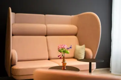 a living room with a couch and a vase with flowers at IntercityHotel Leiden in Leiden