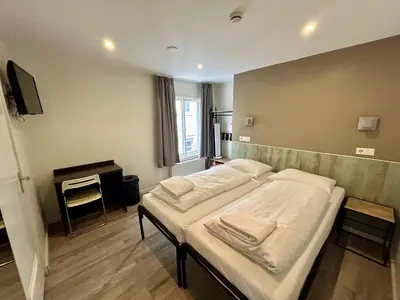 a room with a bed with white pillows on it at Hotel Damrak Inn in Amsterdam