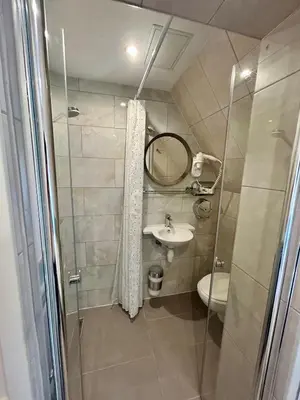 a bathroom with a shower and a sink and a toilet at Hotel Damrak Inn in Amsterdam