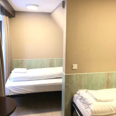a room with two beds and a table in it at Hotel Damrak Inn in Amsterdam