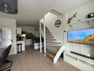 a white staircase in a living room with a kitchen at Palm Beach House in Zandvoort