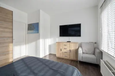 a bedroom with a bed and a tv and a chair at Palm Beach House in Zandvoort