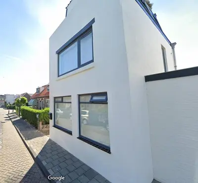 a white building with windows on a street at Palm Beach House in Zandvoort