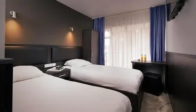 a hotel room with two beds and a window at Belfort Hotel in Amsterdam