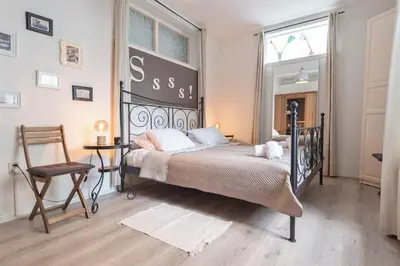 a bedroom with a bed and a chair and a window at Historical Tiny Home (+Private Sauna) in Zandvoort