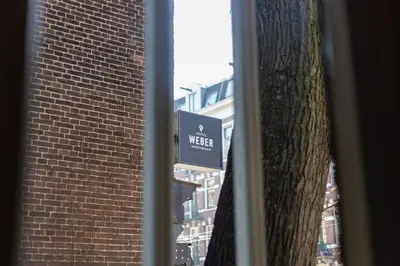 a sign on a tree next to a brick building at Weber Hotel 397 in Amsterdam