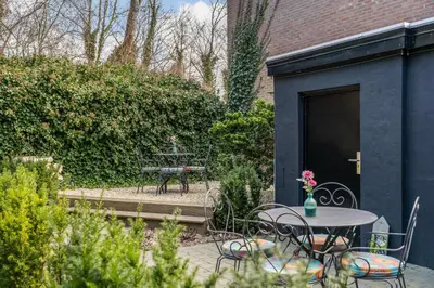 a patio with a table and chairs in a garden at Boutique Pension Code Rosé in Noordwijk