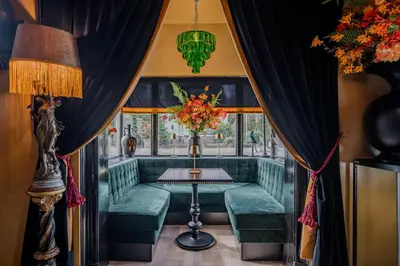 a dining room with a green couch and a table at Boutique Pension Code Rosé in Noordwijk