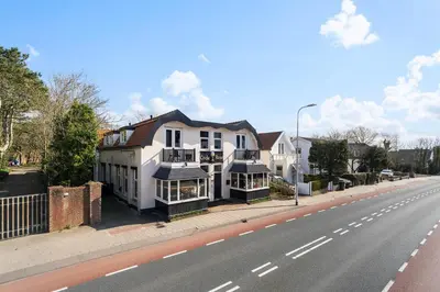 a large white house on the side of a street at Boutique Pension Code Rosé in Noordwijk