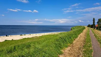 a dirt road leading to a beach next to the water at Aan de Dijk in Edam