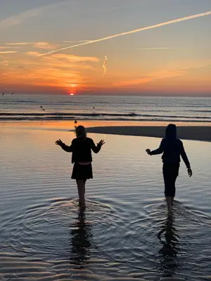 two women walking in the water on the beach at sunset at Kahakai Beach House - Unique Outdoor Kitchen - next to local lake and 15 min. the from beach in Noordwijkerhout