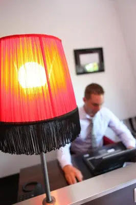 a man sitting at a desk with a laptop and a lamp at Hotel Mijdrecht Marickenland in Mijdrecht