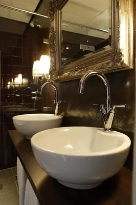 a bathroom with two white sinks and a mirror at Hotel Mijdrecht Marickenland in Mijdrecht