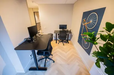 an office with two desks with chairs and a bicycle on the wall at Alphabet Apartments - Kerkstraat 71 in Hilversum