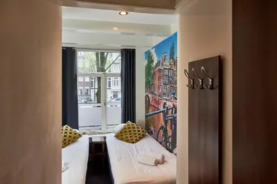 a small room with two beds and a window at ITC Hotel in Amsterdam