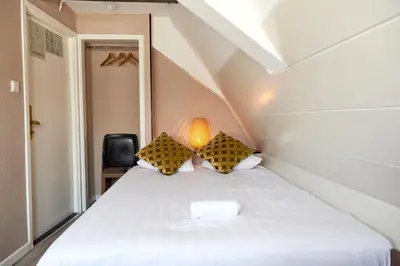 a bedroom with a white bed with a lamp at ITC Hotel in Amsterdam