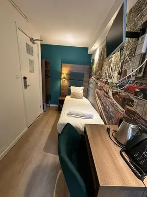 a hotel room with a bed and a desk with a phone at ITC Hotel in Amsterdam