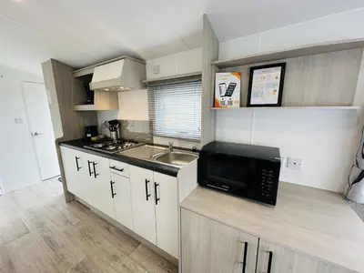a small kitchen with a microwave and a sink at DD 58 - Camping de Duindoorn - AIRCO in IJmuiden
