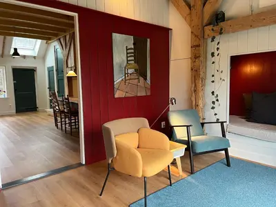 a living room with a chair and a table at Kleinhoef - charmante, luxe kamers in een boerderij uit 1875 in Nigtevecht