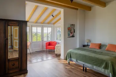 a bedroom with a bed and a red chair at Kleinhoef - charmante, luxe kamers in een boerderij uit 1875 in Nigtevecht