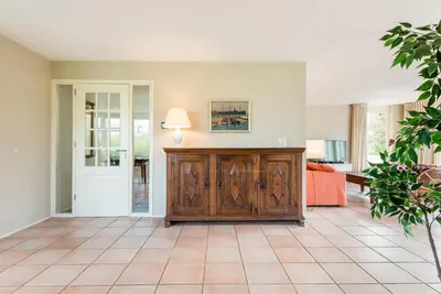 a living room with a wooden cabinet and a couch at Villa Duin en Strand in Bergen aan Zee