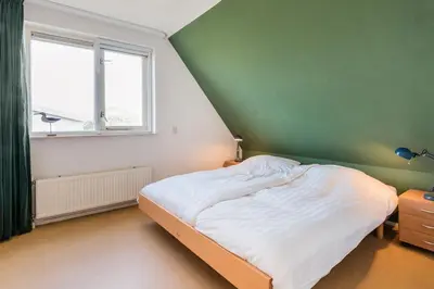 a green and white bedroom with a bed and a window at Villa Duin en Strand in Bergen aan Zee