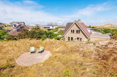 two chairs and a house on top of a hill at Villa Duin en Strand in Bergen aan Zee
