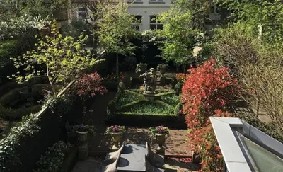 a garden with a fountain and many plants at Dutch Masters Short Stay Apartments in Amsterdam