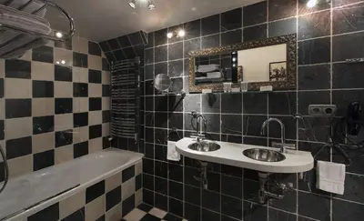 a black and white tiled bathroom with two sinks and a tub at Dutch Masters Short Stay Apartments in Amsterdam