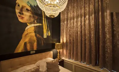 a painting of a woman is hanging above a bed at Dutch Masters Short Stay Apartments in Amsterdam